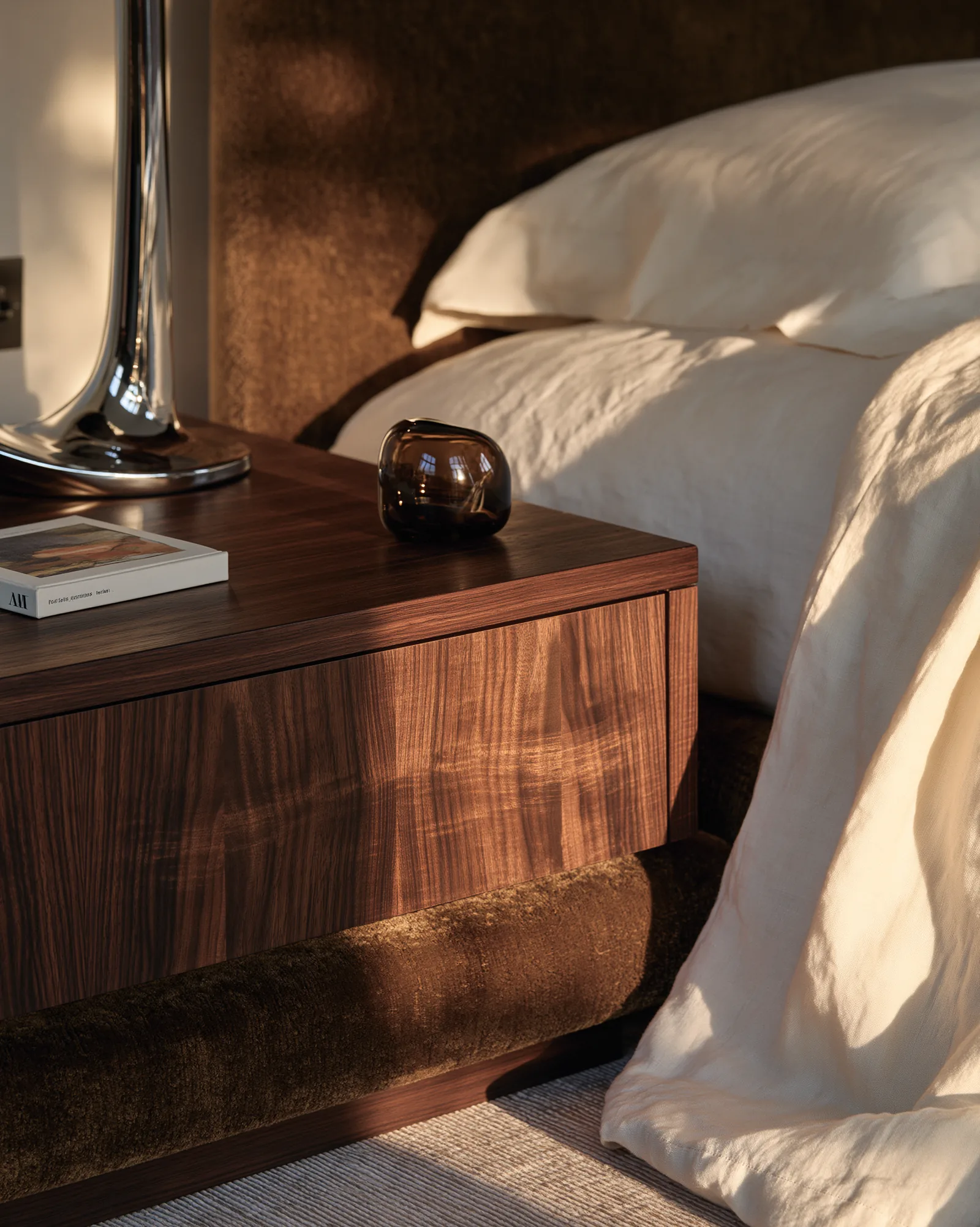 Walnut bedside cabinet against a bronze velvet headboard
