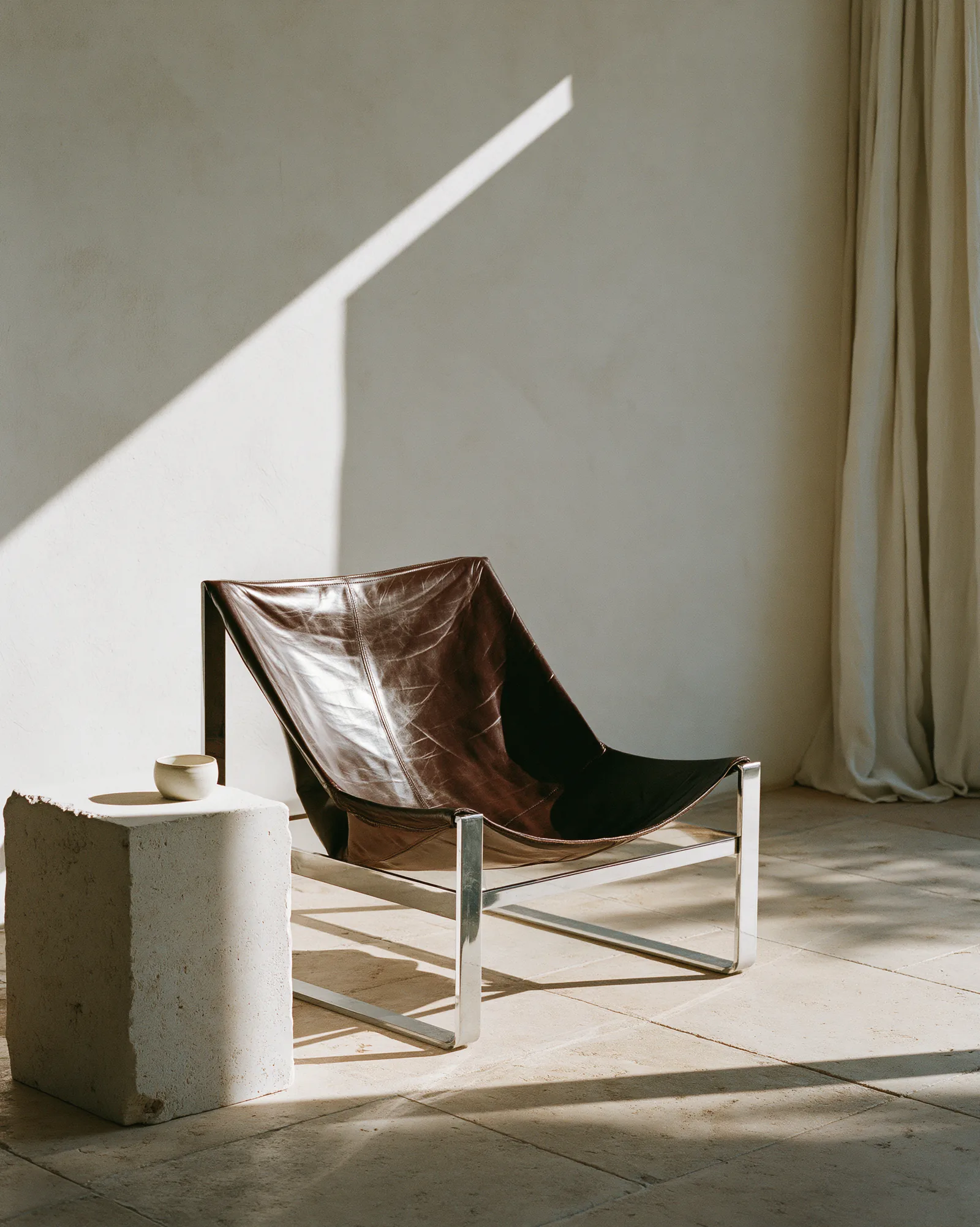 Patinated brown leather sling chair on a polished chrome frame